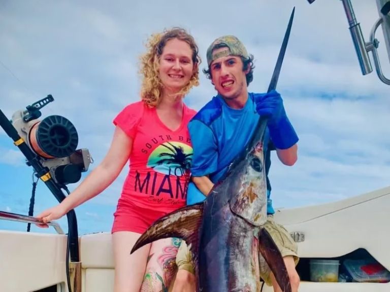 A man and a woman holding a large fish on a boat