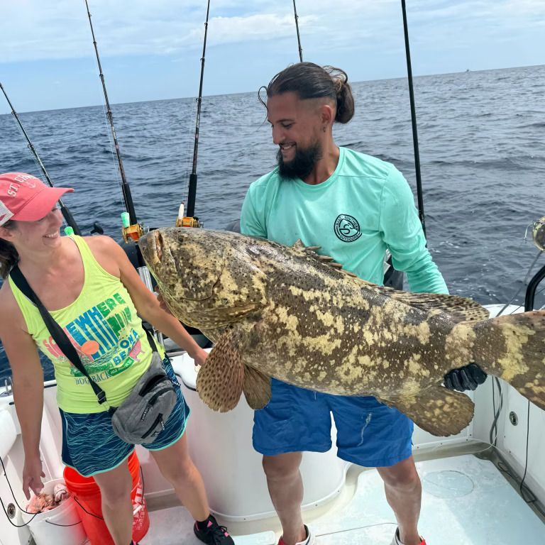 A man and a woman holding a large fish on a boat