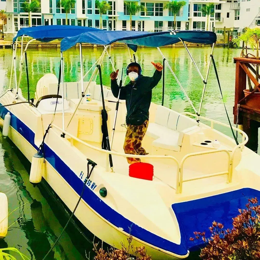 A man wearing a mask is standing on a boat with a blue canopy