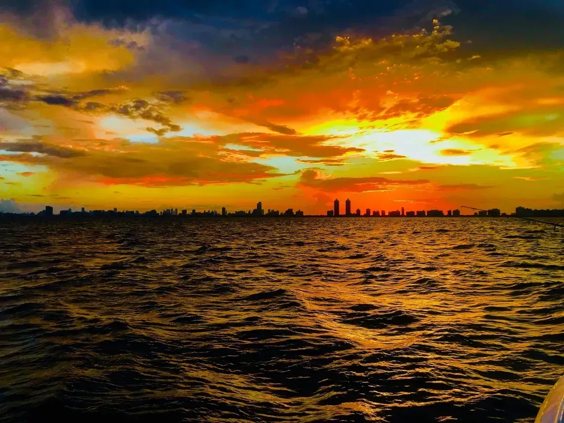 A sunset over a body of water with a city in the background.