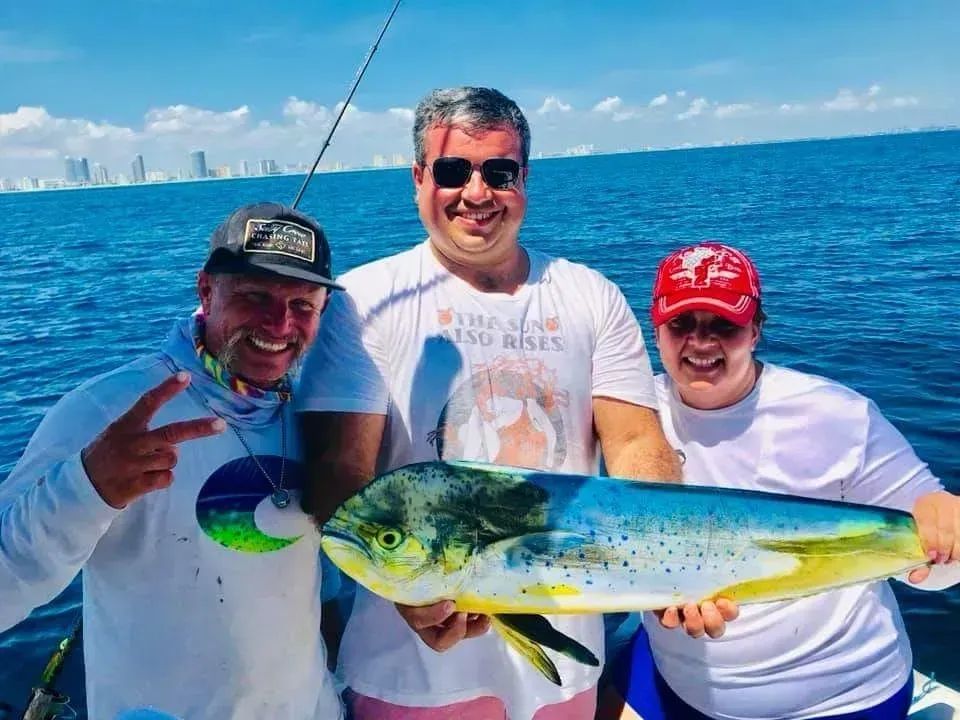 Three men are standing on a boat holding a large fish.
