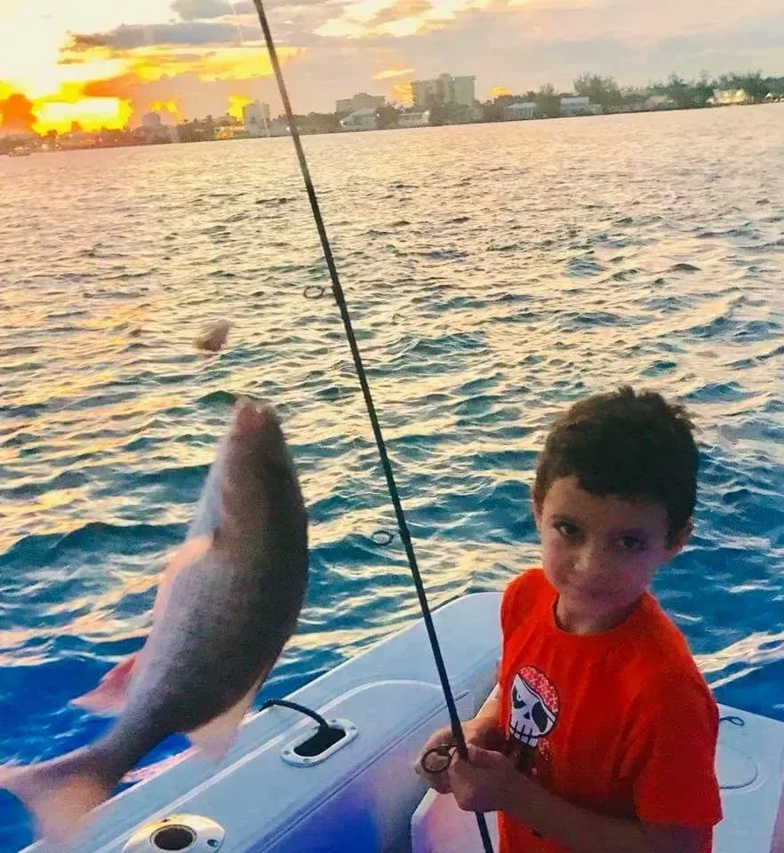 A young boy is fishing in the ocean on a boat.
