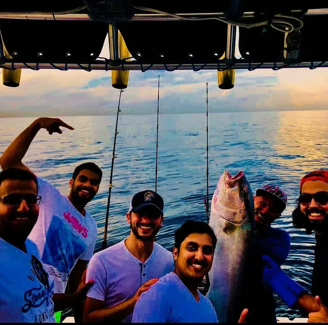 A group of men on a boat holding a large fish