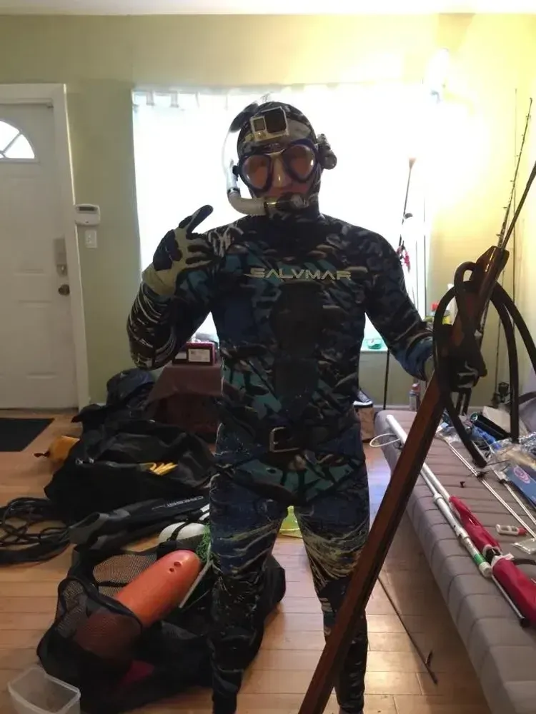 man wearing a dive suit and holding a speargun for spearfishing