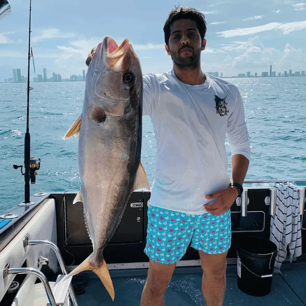A man is holding a large fish on a boat