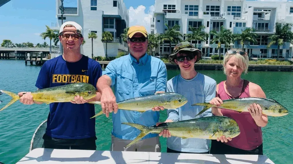 A group of people are standing on a boat holding fish.