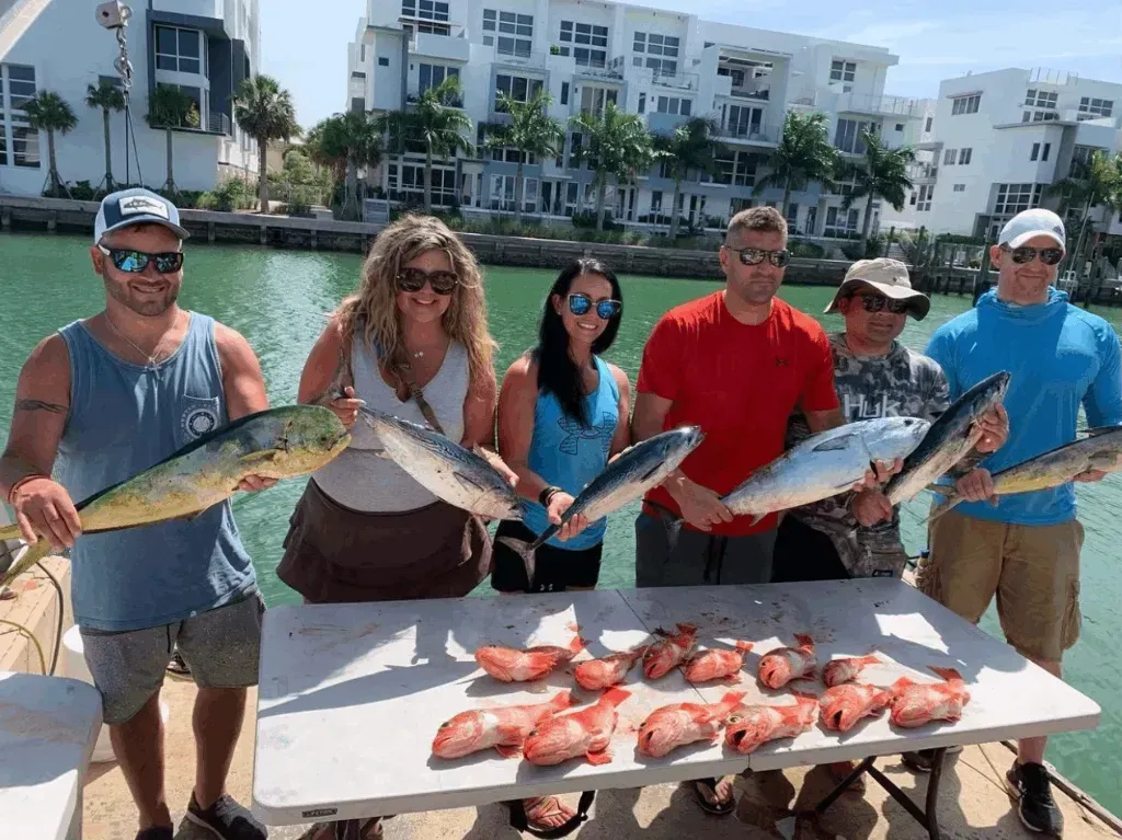 A group of people are standing around a table holding fish.
