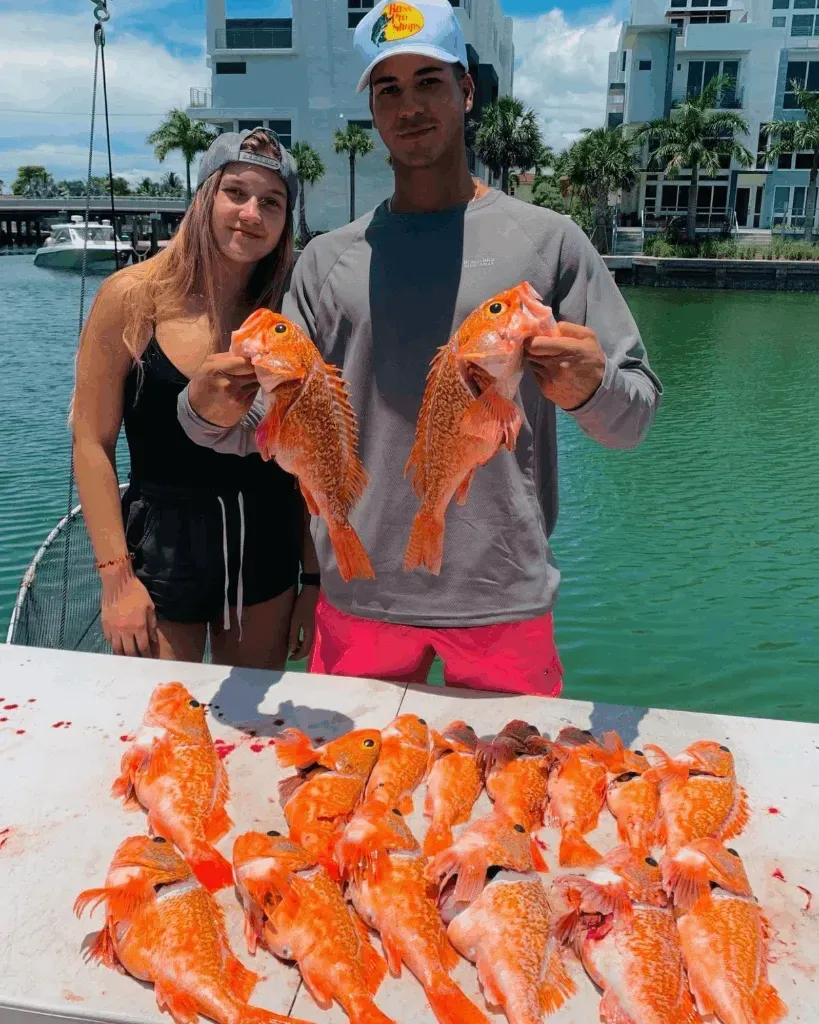 A man and a woman are holding fish on a boat.