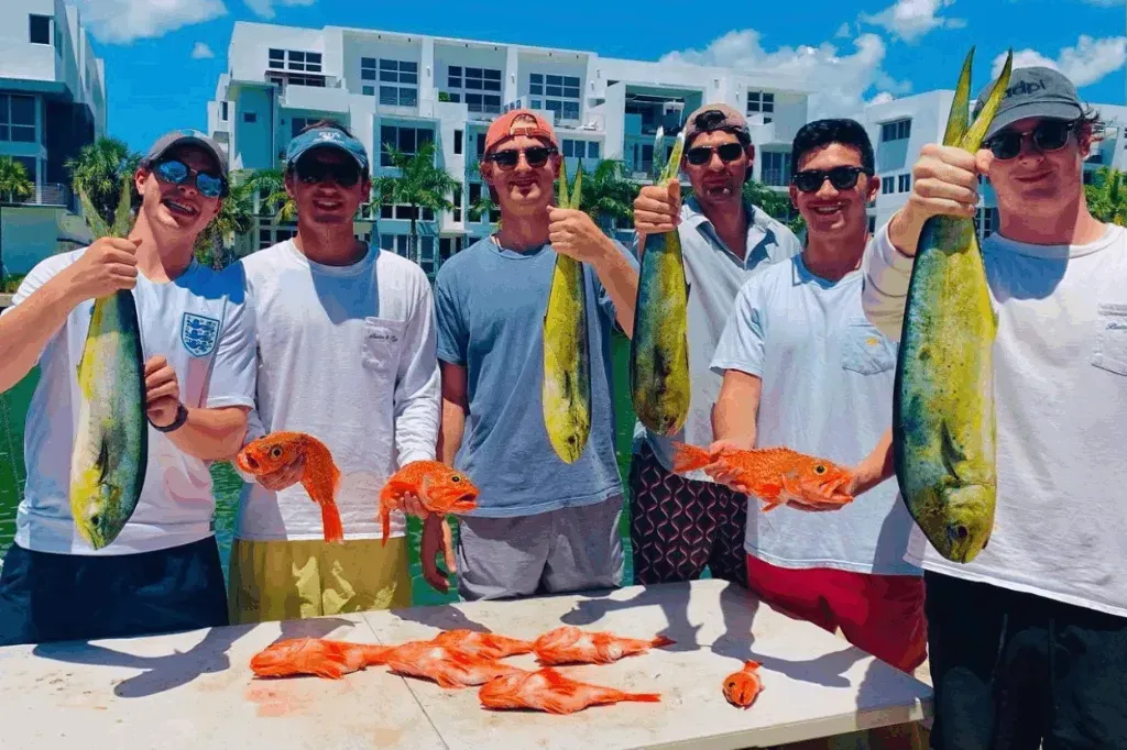 A group of men are standing around a table holding fish.