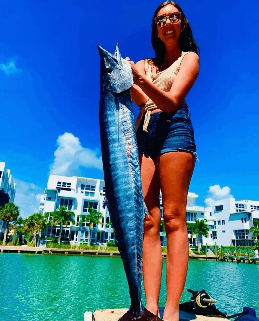 A woman is standing on a dock holding a large fish
