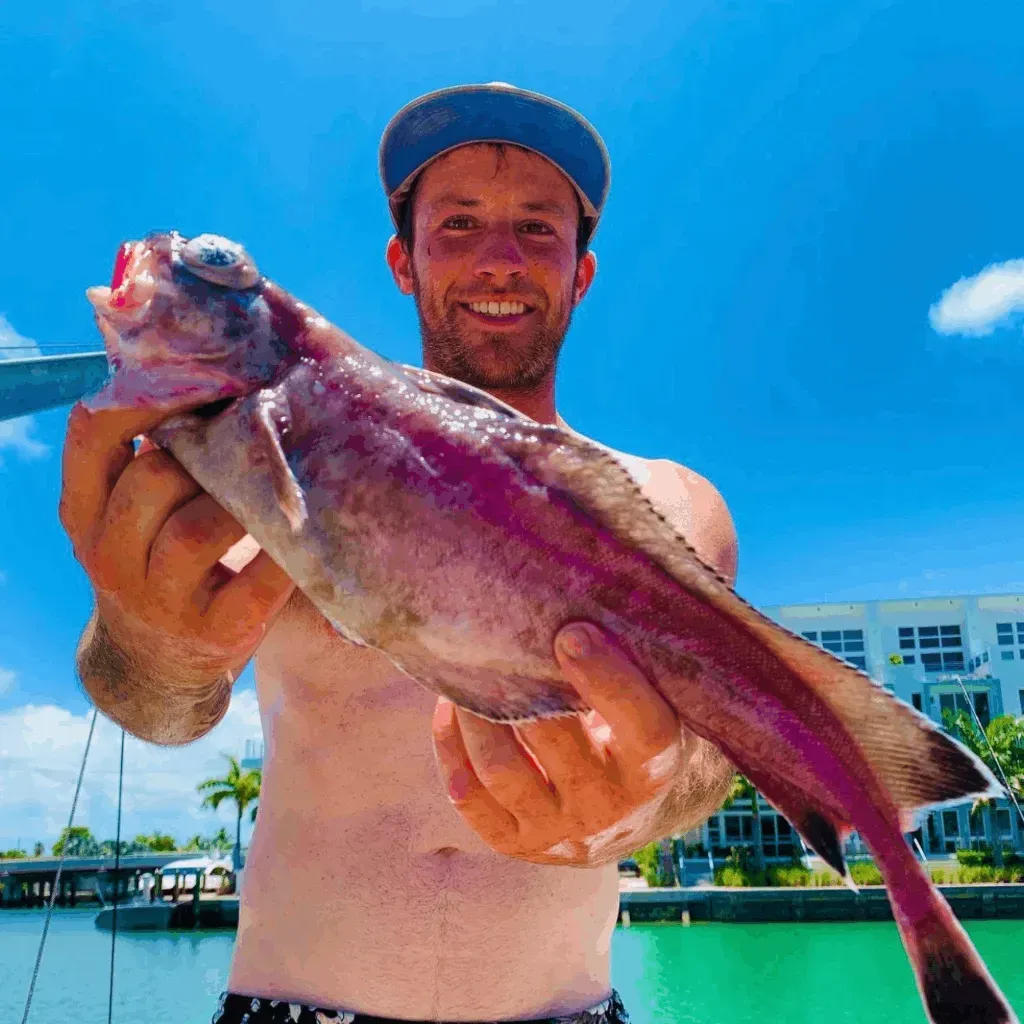 A shirtless man is holding a large fish in his hands