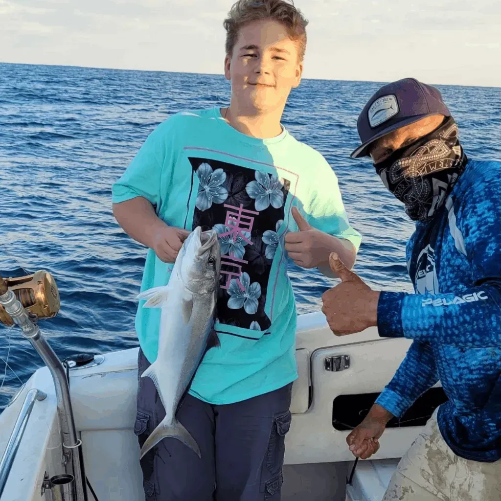 A man and a boy are standing on a boat holding a fish.