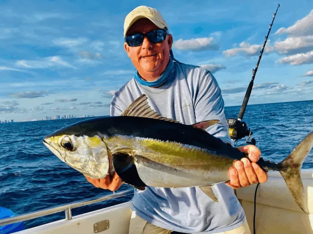 A man is holding a large fish on a boat in the ocean.