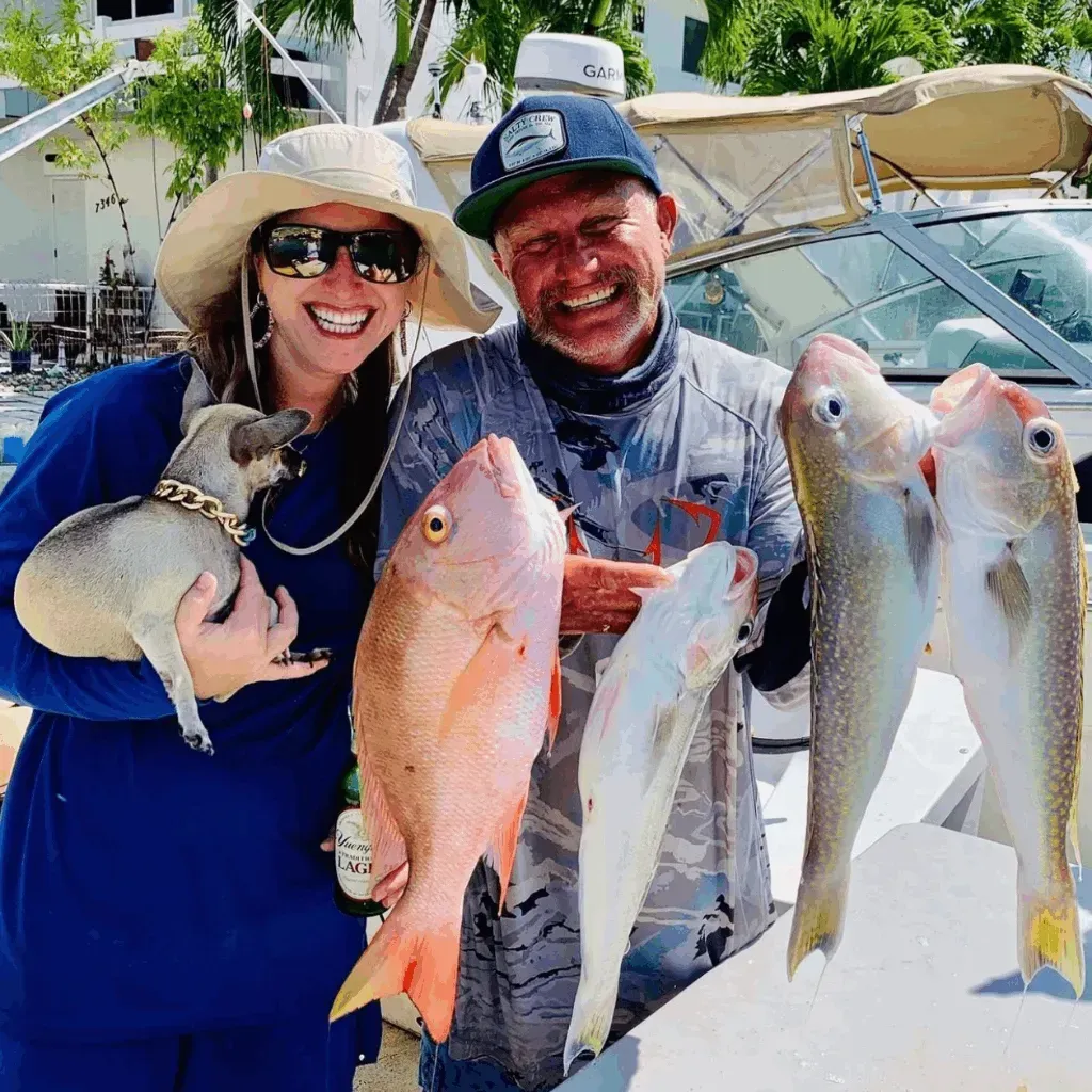 A man and a woman are holding fish in front of a boat.