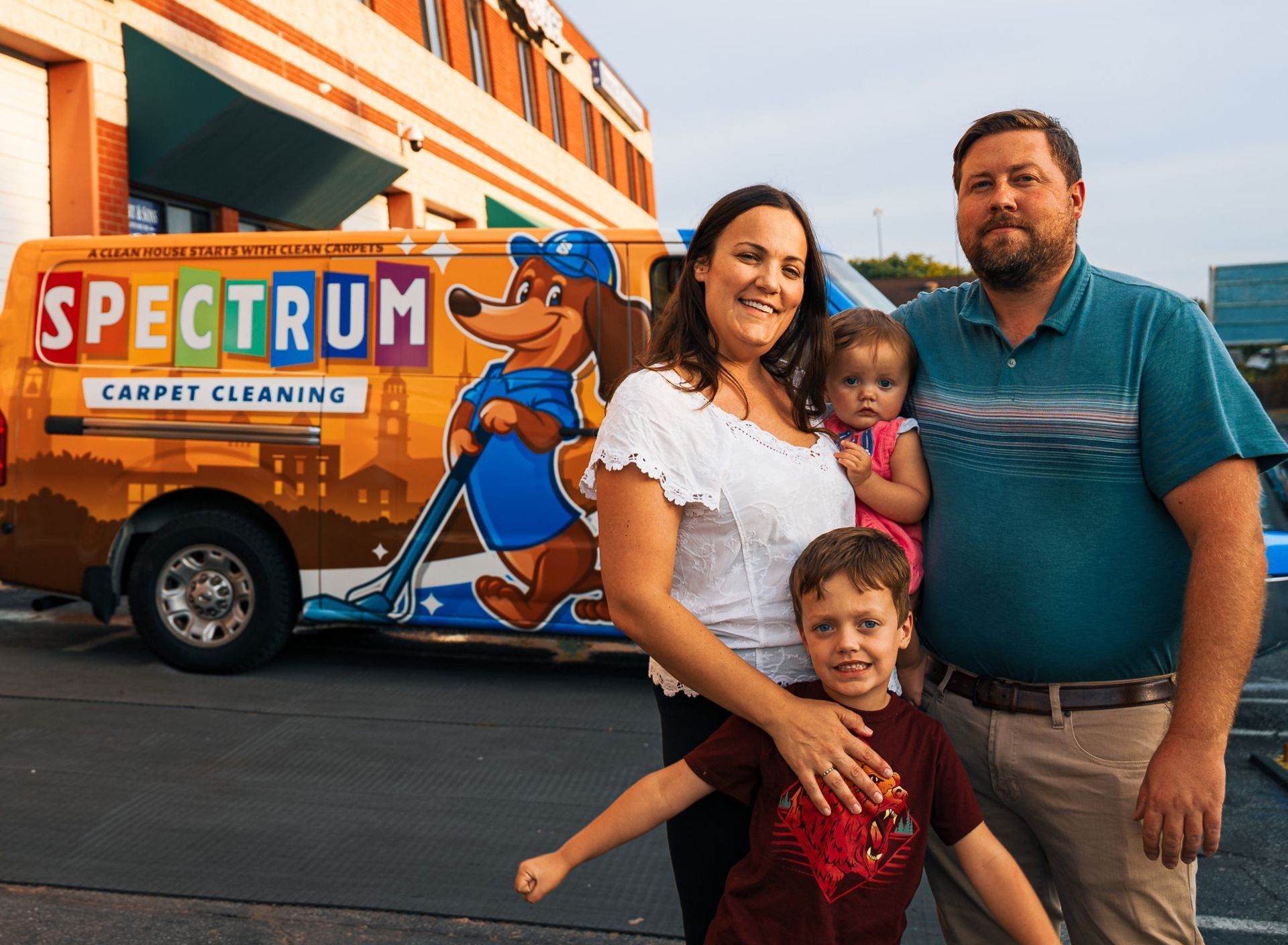 Family poses with Spectrum Carpet Cleaning van, smiling.