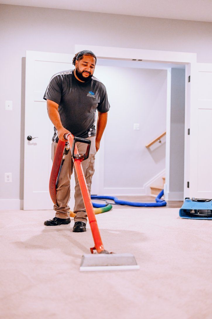Person using a floor sander on a carpeted room floor during renovation