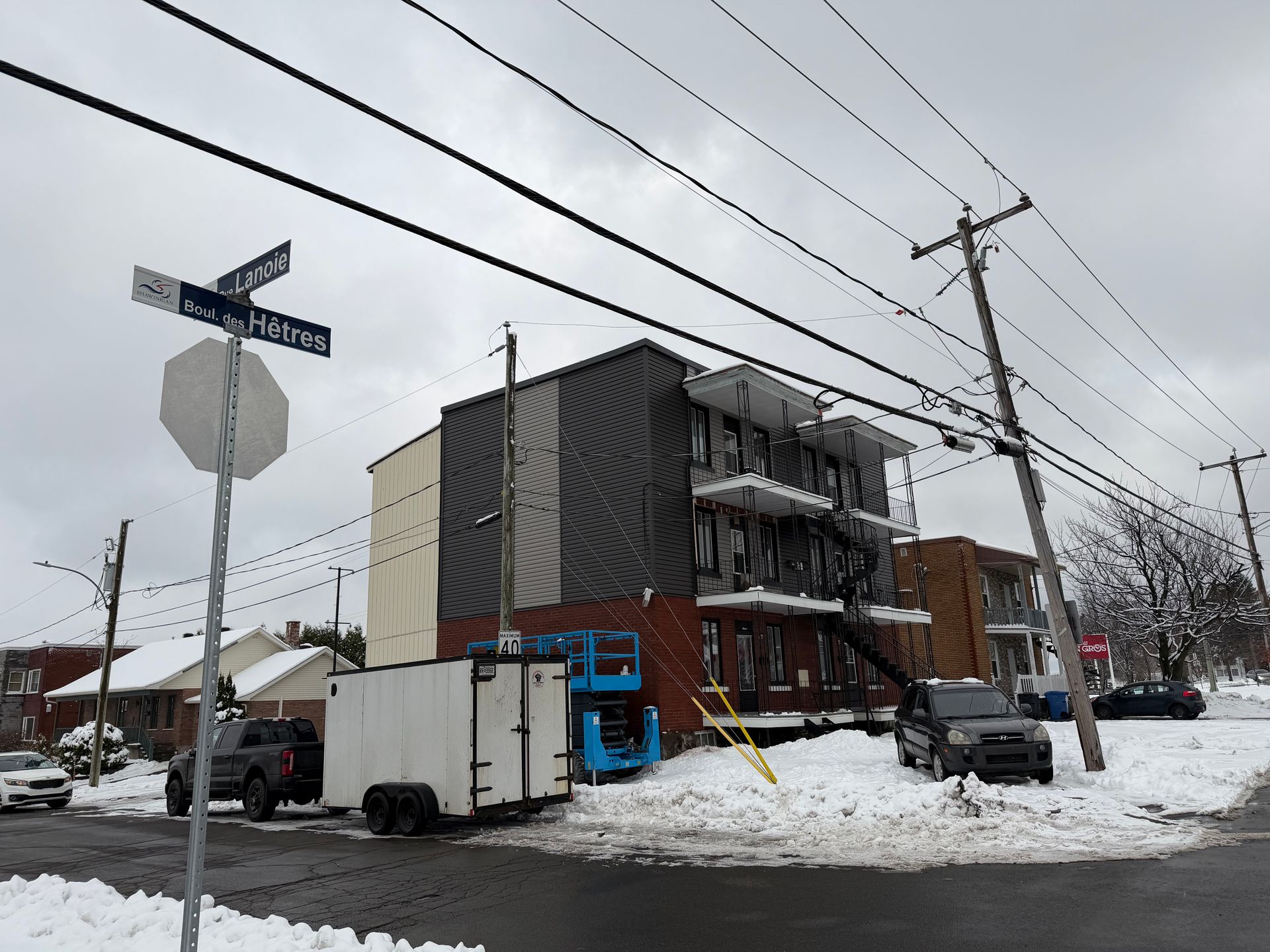 Immeuble d'appartements endommagé par un incendie, rue enneigée, poteaux électriques, panneau de signalisation.