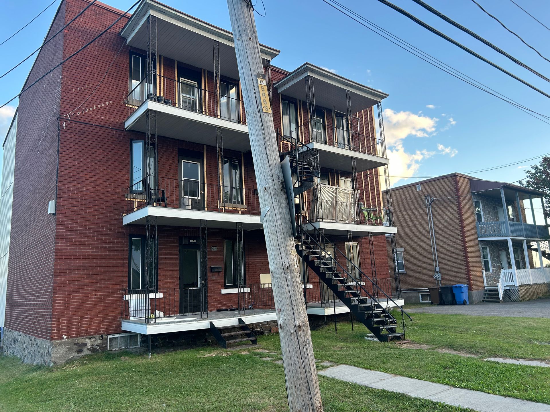 Immeuble d'appartements en briques avec cage d'escalier extérieure ; poteau électrique au premier plan.