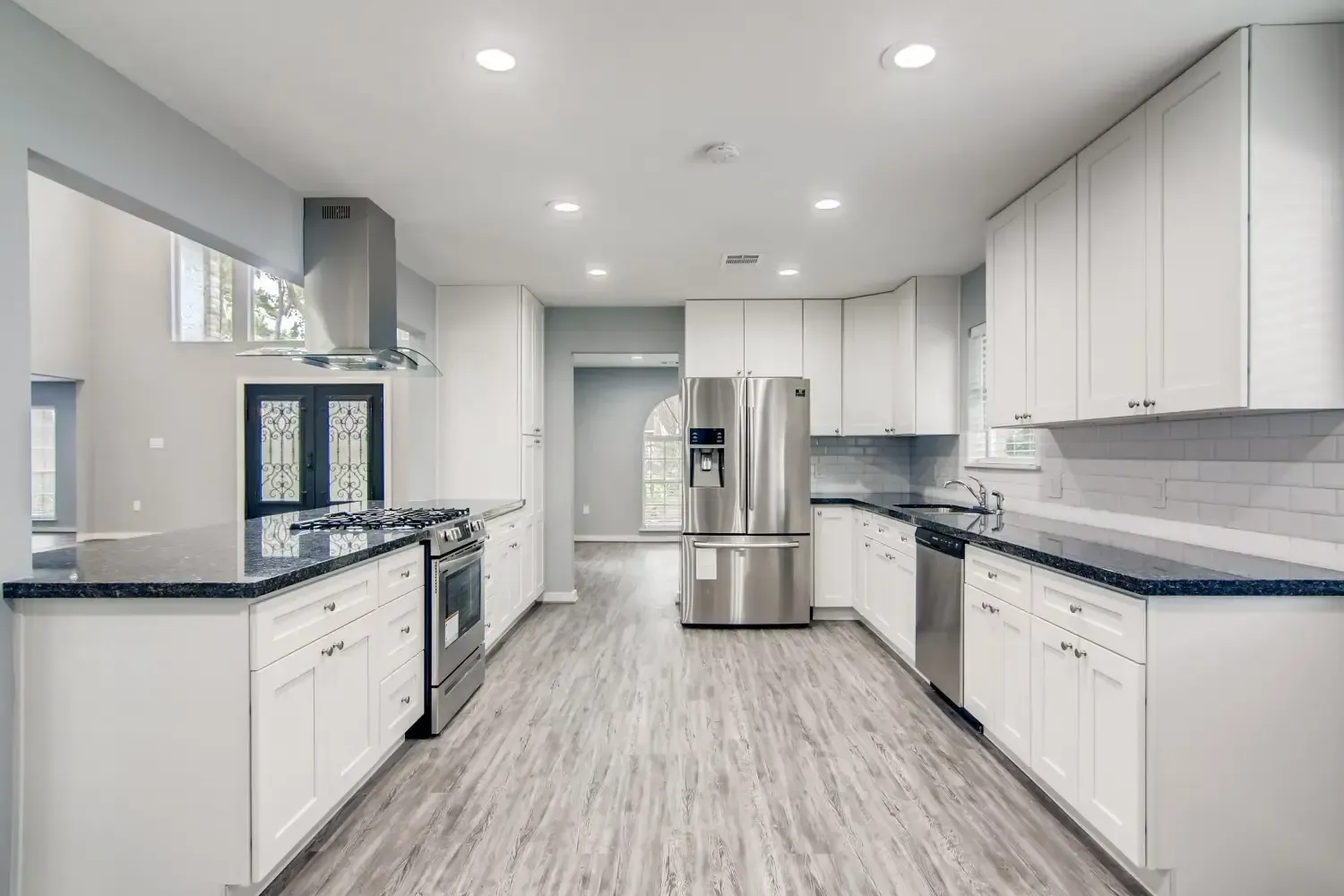 A large kitchen with white cabinets and stainless steel appliances and custom flooring