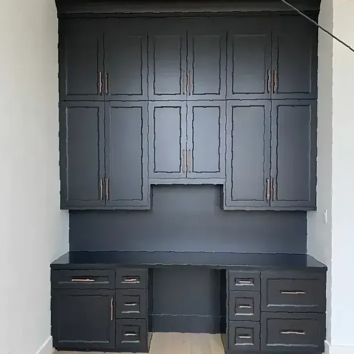 A kitchen with black cabinets and drawers and a desk.