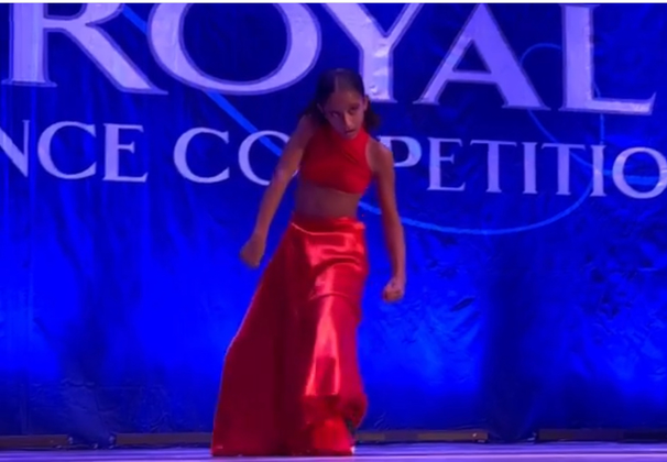 Young dancer in red outfit performing on stage.