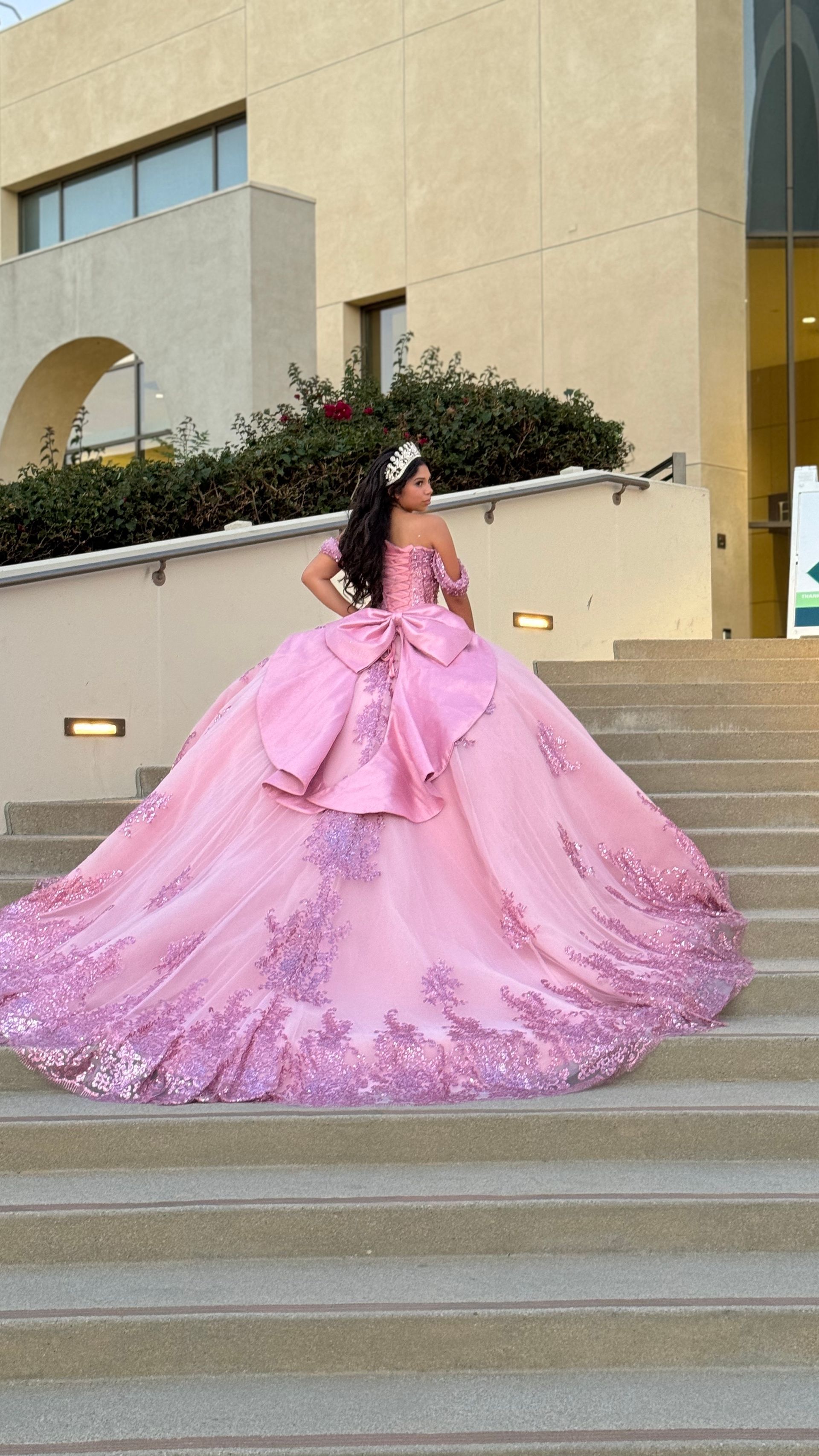 A woman in a black and white ball gown is standing in front of a wall of flowers.