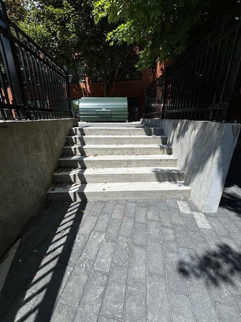 Un escalier menant à une poubelle verte
