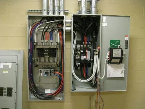 A couple of electrical boxes hanging on a wall with wires coming out of them.