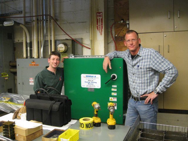 Two men standing next to a green box that says do not mount