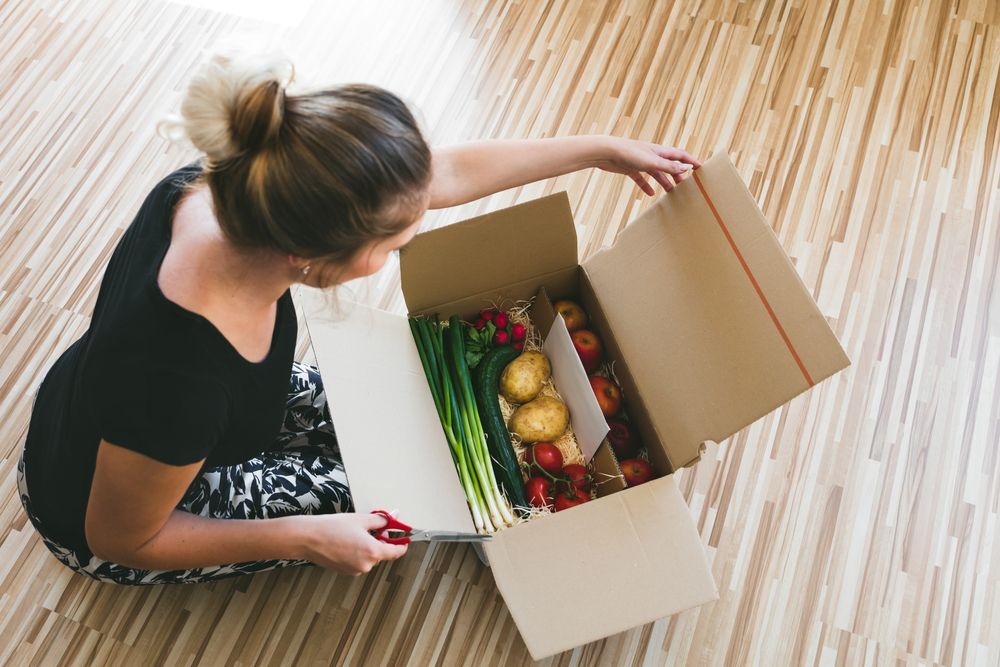 Woman Opening a Vegetable delivery box at home — Fresh to Door In Fyshwick ACT