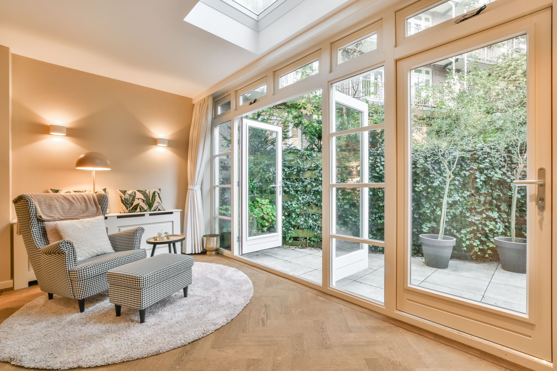 A living room with a chair and ottoman and a lot of windows.