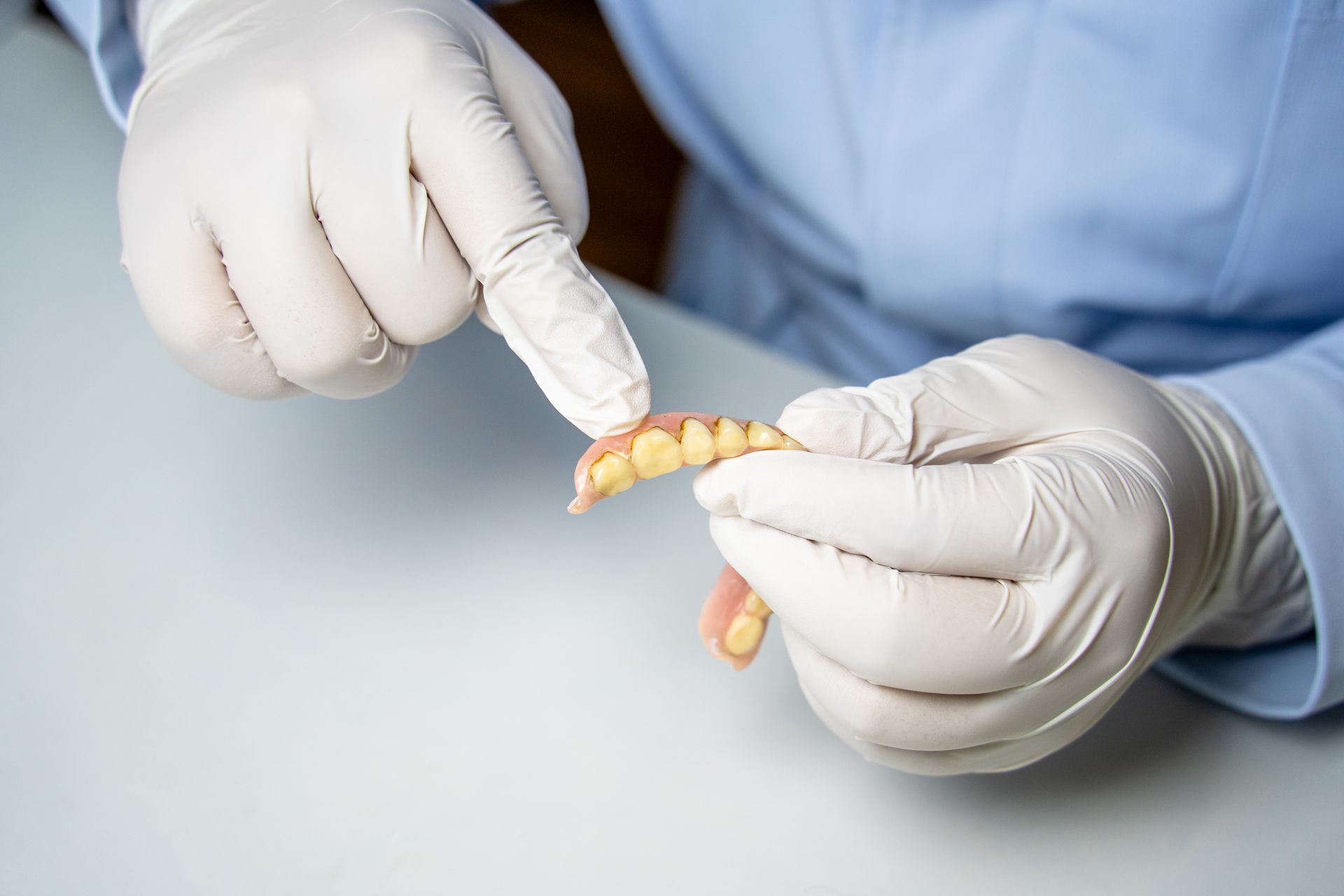 Dental professional holding removable partial denture for display.