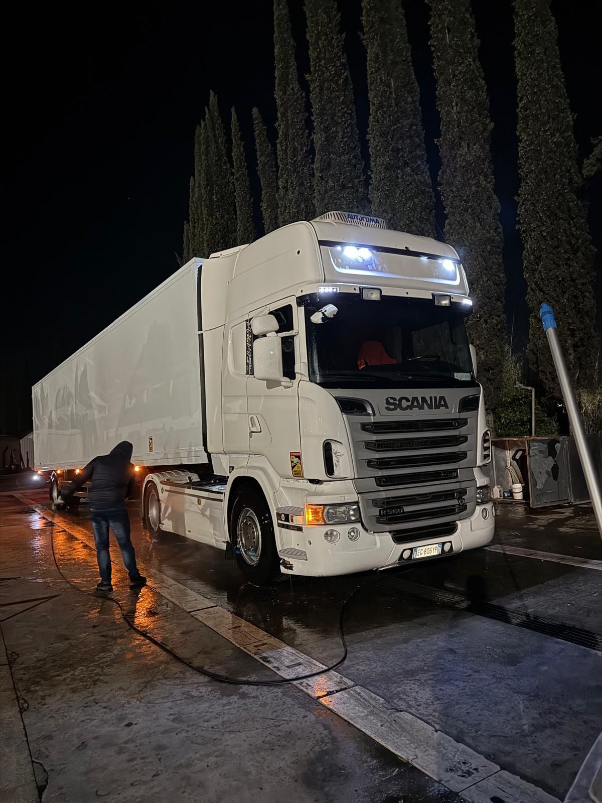 Un uomo sta lavando un camion bianco di notte.