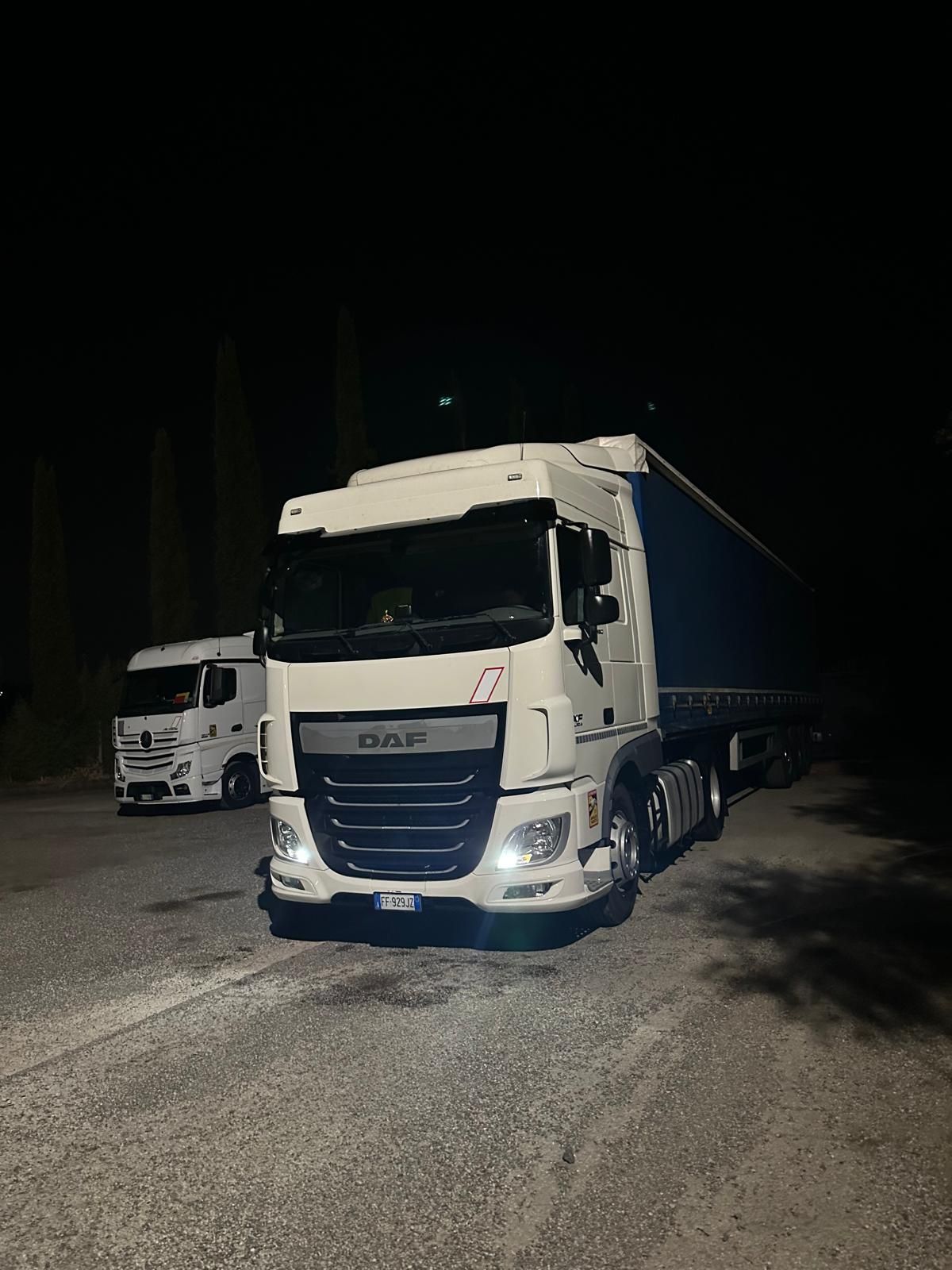 Due camion sono parcheggiati in un parcheggio di notte.