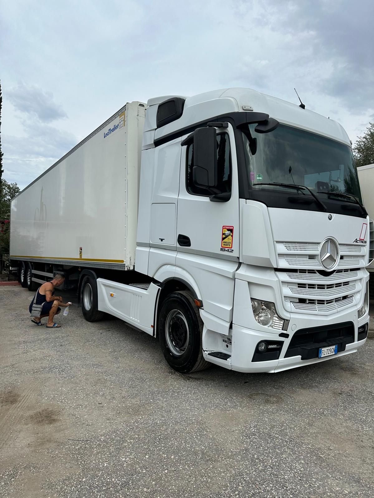 Un camion bianco è parcheggiato in uno spiazzo ghiaioso.
