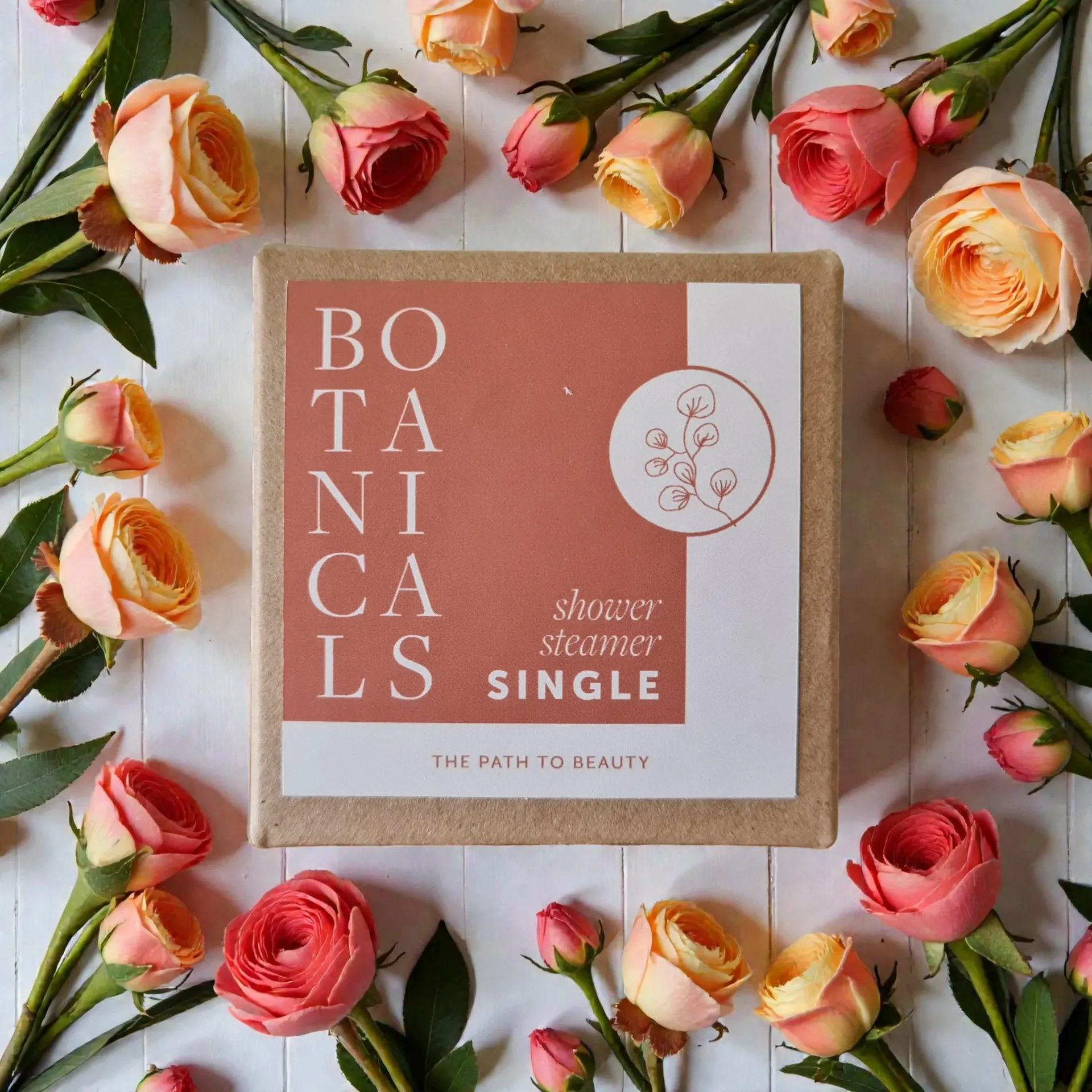 Botanicals gift box with a shower steamer, surrounded by pink and yellow flowers on a white background