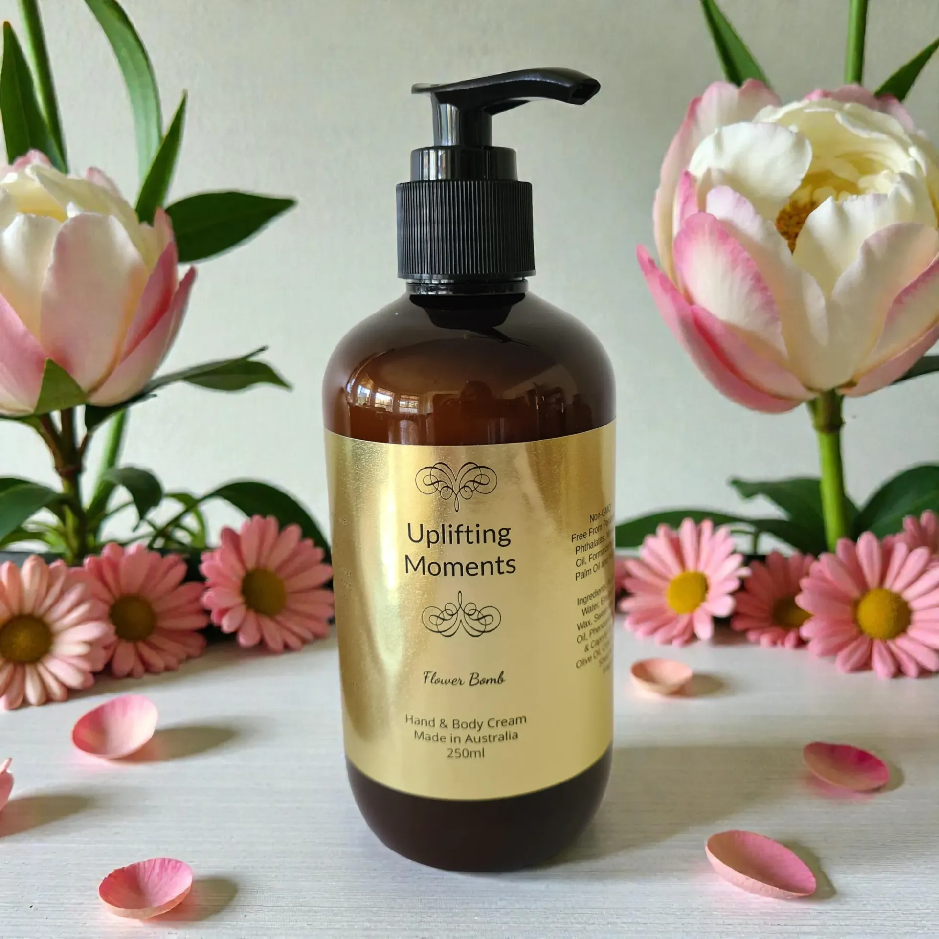 Amber pump bottle of Flower Bomb type body lotion with pink flowers and petals on a white surface
