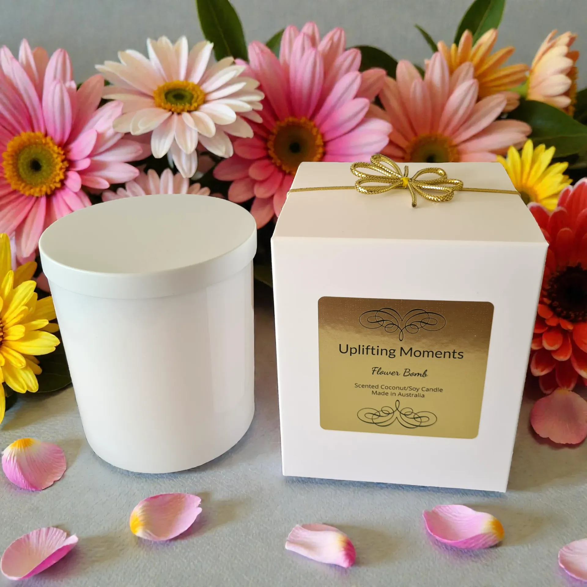 White candle with lid surrounded by pink and red flowers on a wooden surface