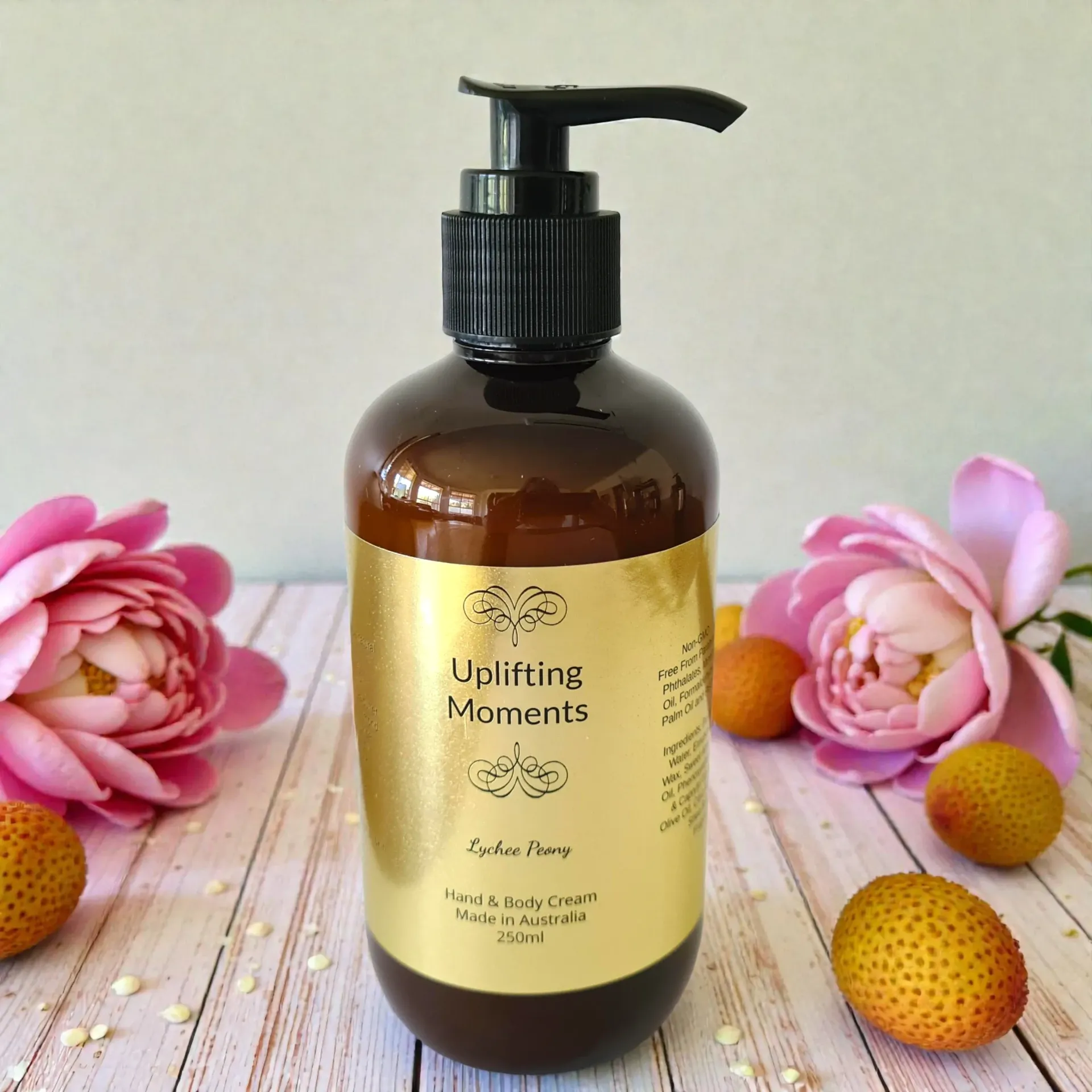 Amber pump bottle of Flower Bomb type body lotion with pink flowers and petals on a white surface