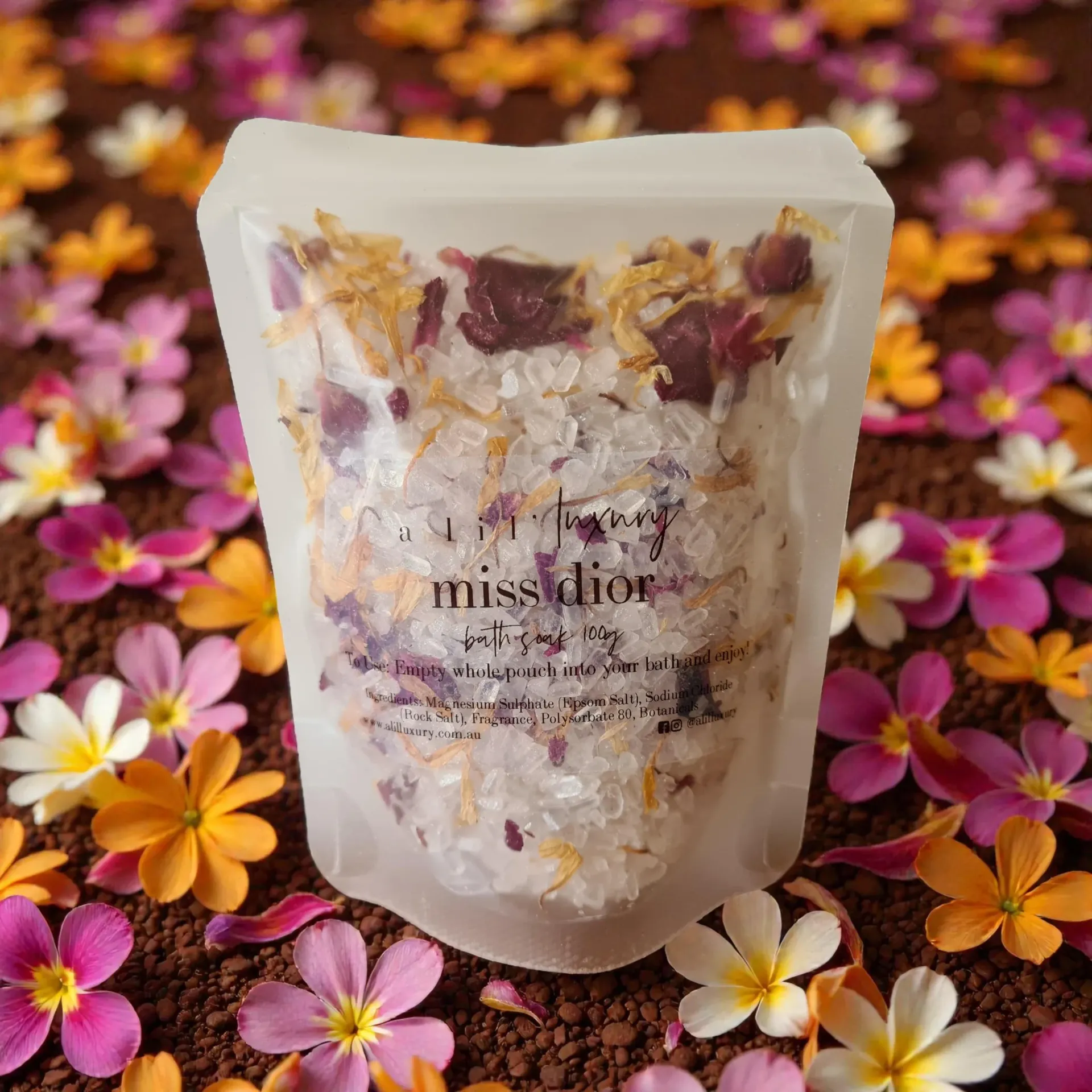Translucent bath salts and dried-flower pouch on a bed of pink and orange petals