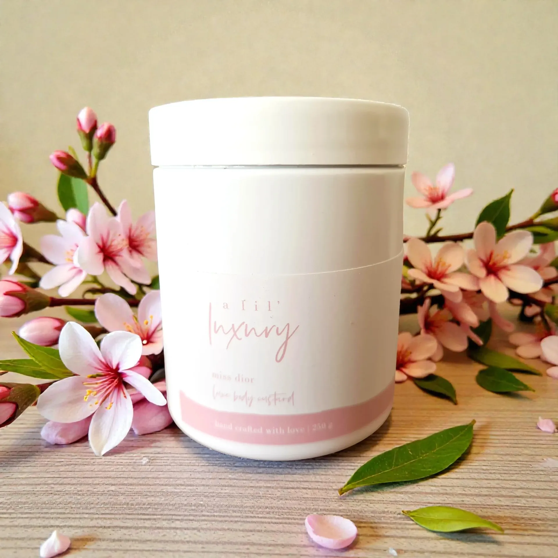 White body custard jar with pink label, surrounded by pink flowers and green leaves on a wooden surface