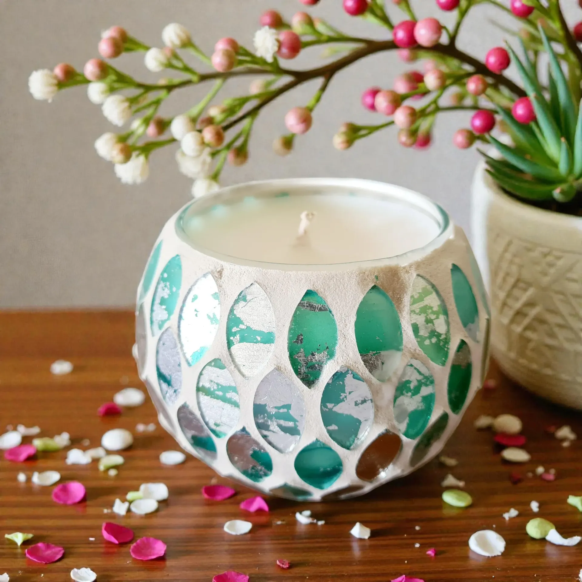 Decorative teal and white candle holder surrounded by scattered petals on a table