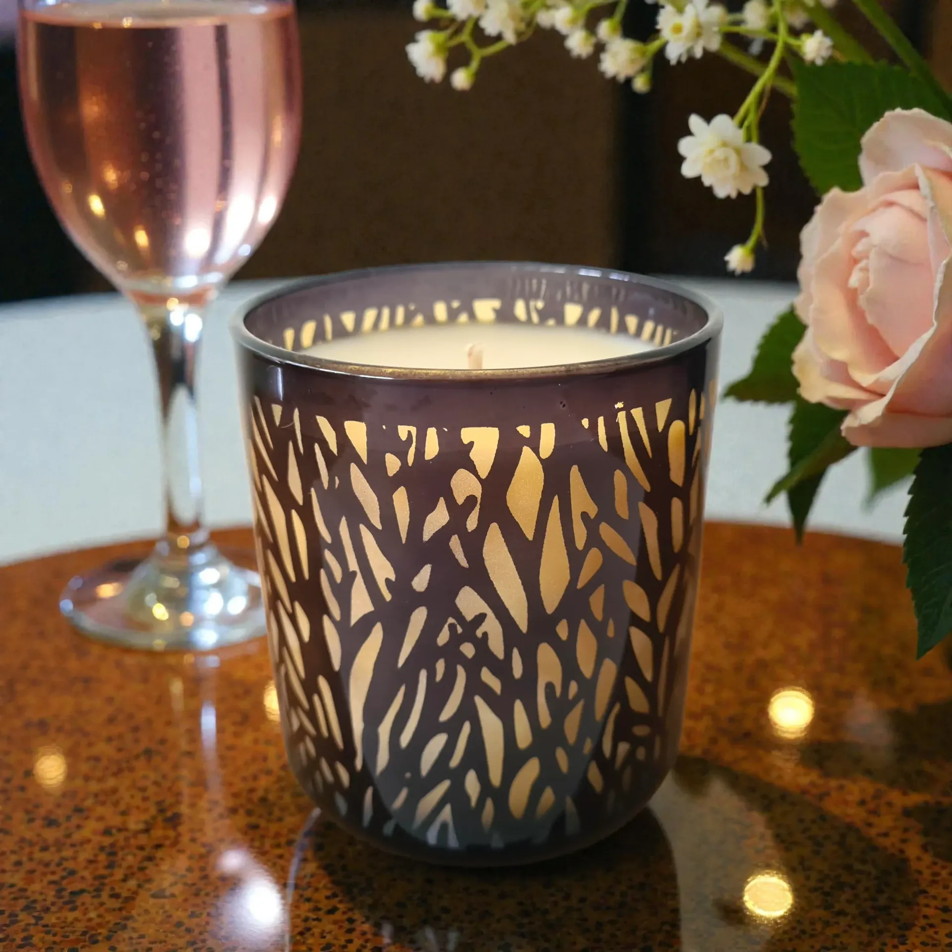 Lacy candle holder on a glossy table beside a pink champagne flute and flowers