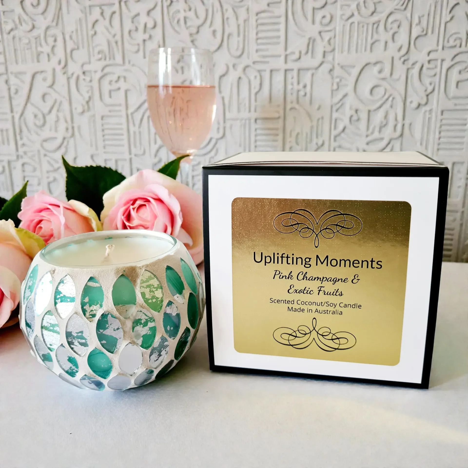 Decorative white-and-teal candle holder with flowers beside a wine glass on a table