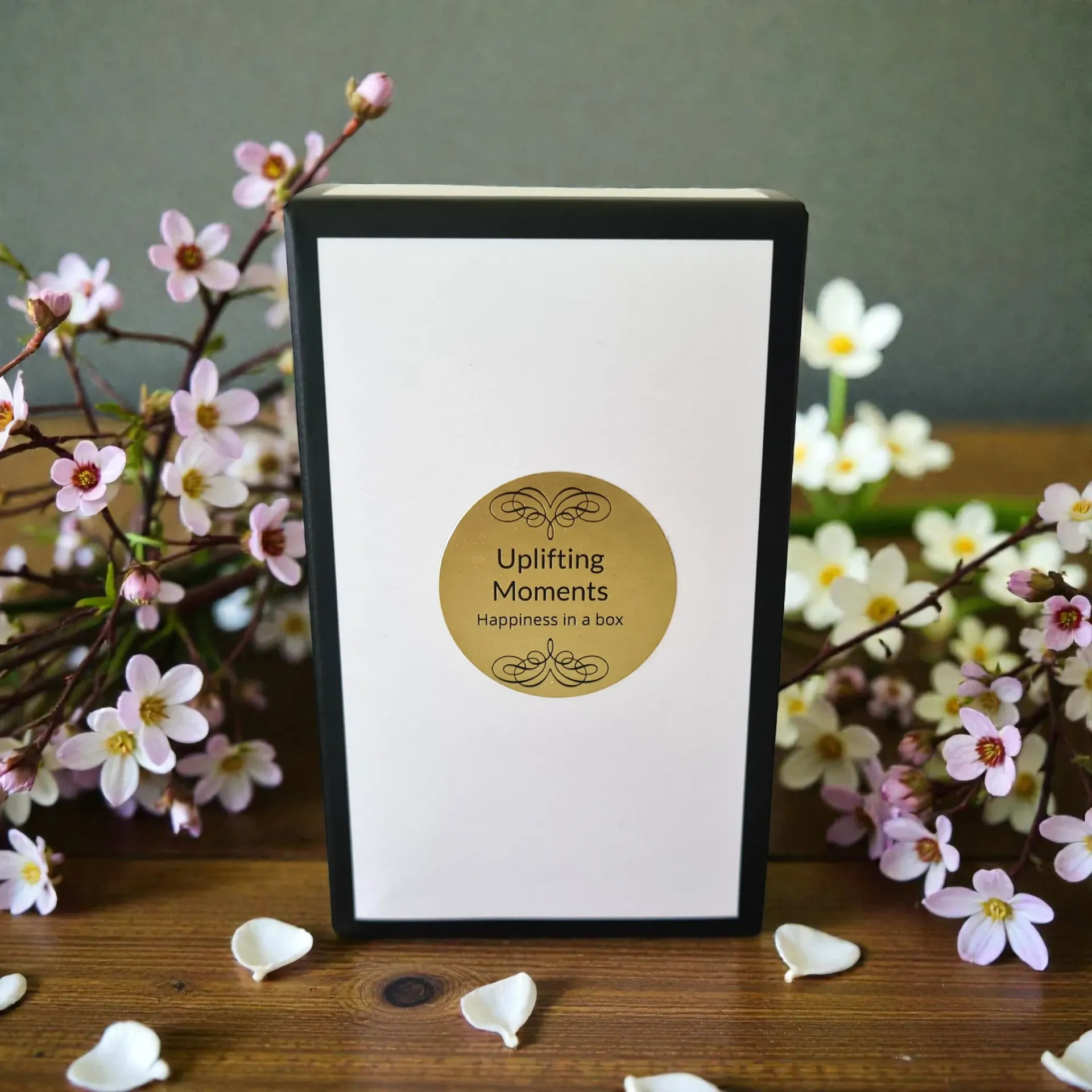 Frosted candle on wooden table with pink and white flowers in a sunlit garden