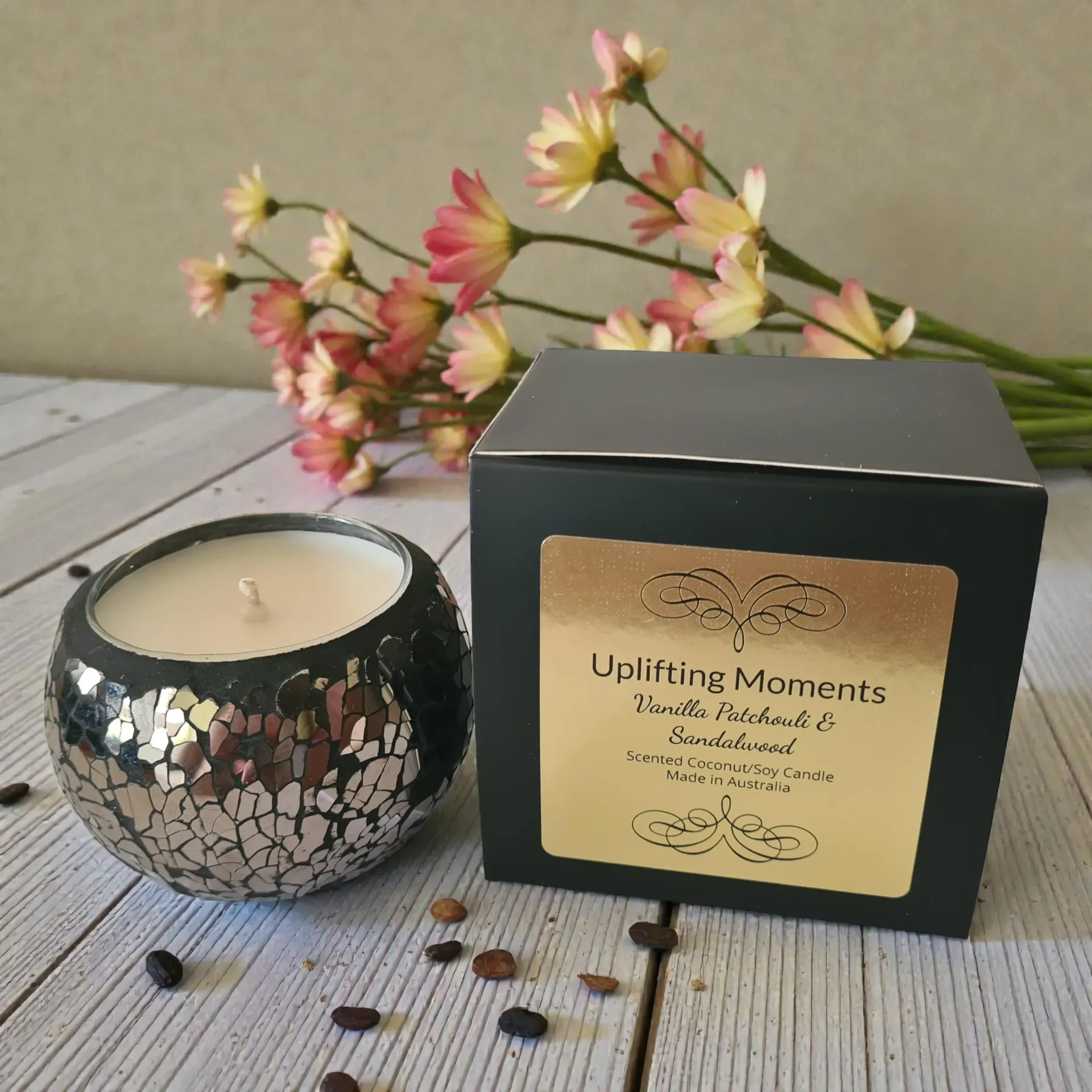 Decorative mosaic candle on a rustic table with white flowers and dried petals around it