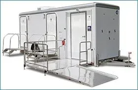 Portable wheelchair-accessible ramp with railings attached to a gray trailer or mobile unit
