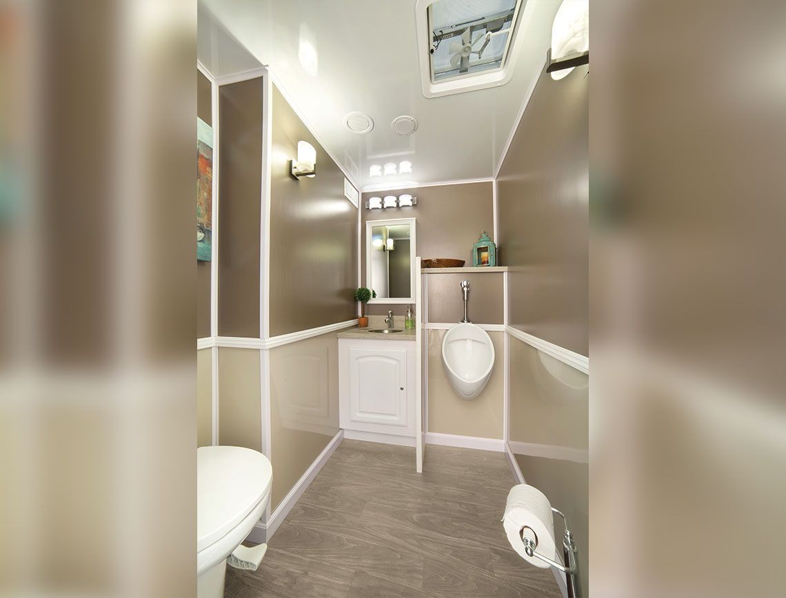 Narrow modern RV bathroom with beige walls, white sink, toilet, shower, and gray floor