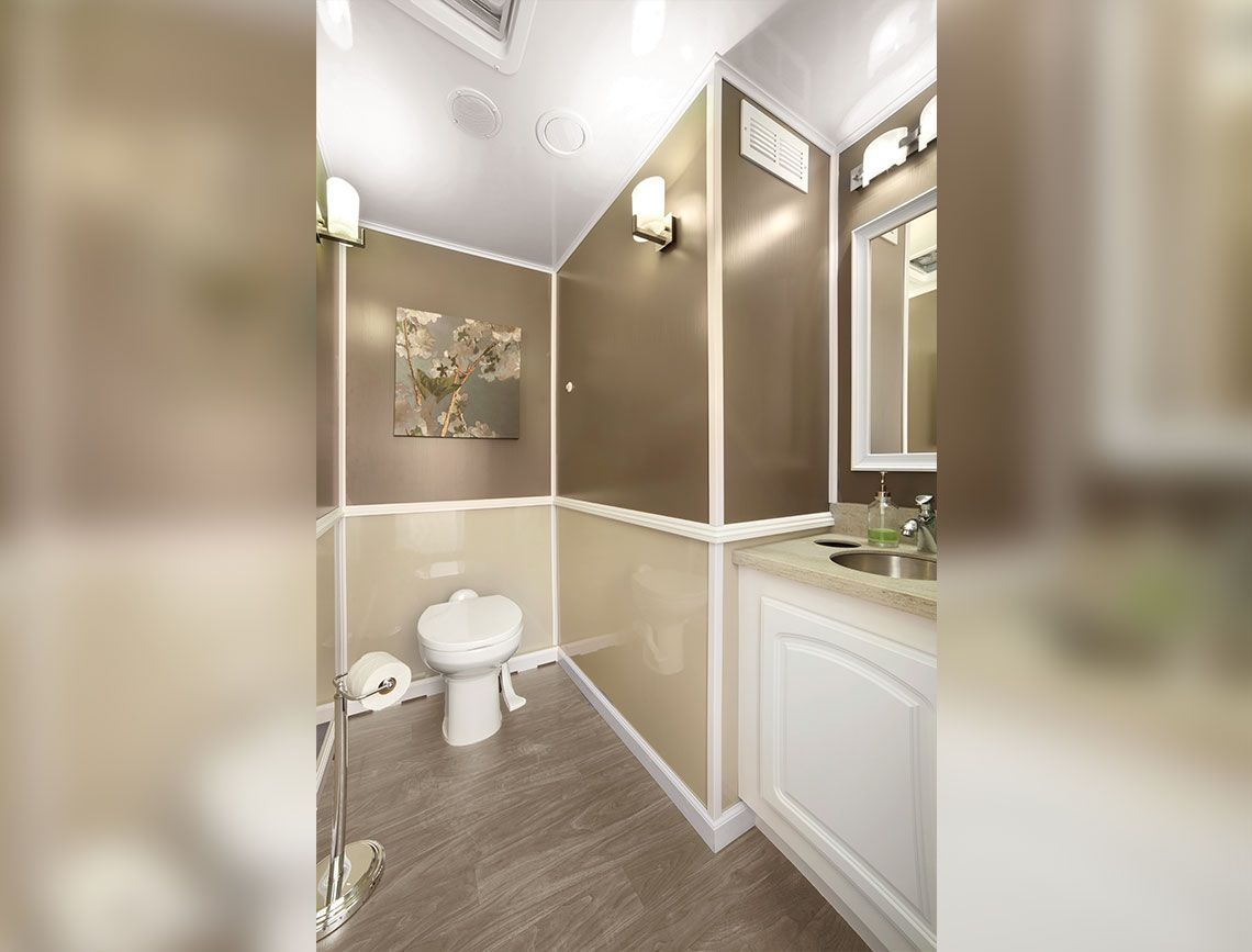 Small beige bathroom with a toilet, vanity, and wall art, viewed from the doorway.