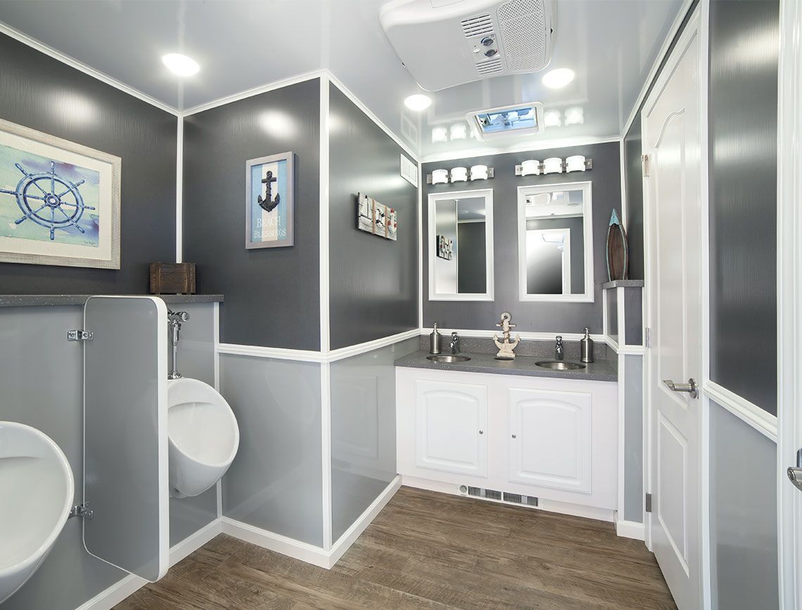 Modern gray and white bathroom with toilet, vanity, mirror, and wood-look floor